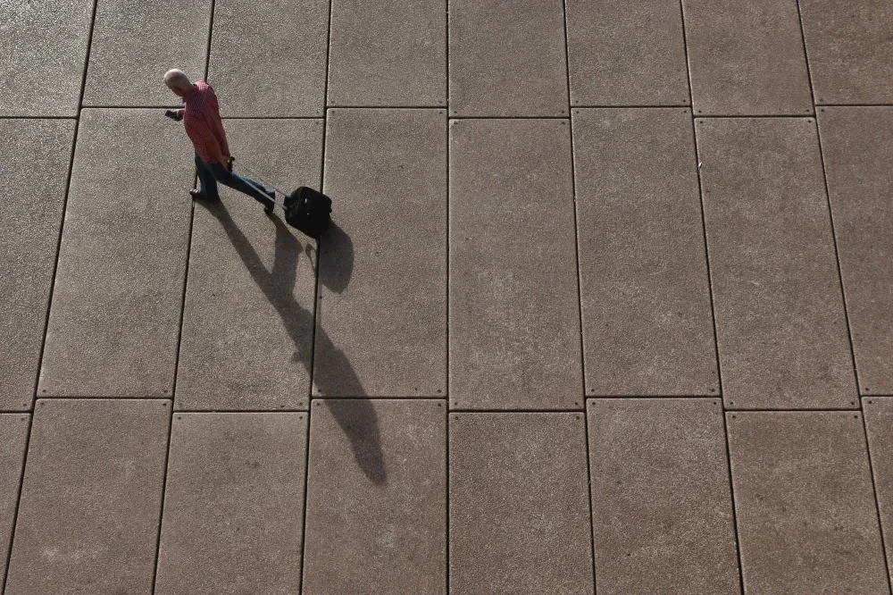 man walking through airport with a suitcase
